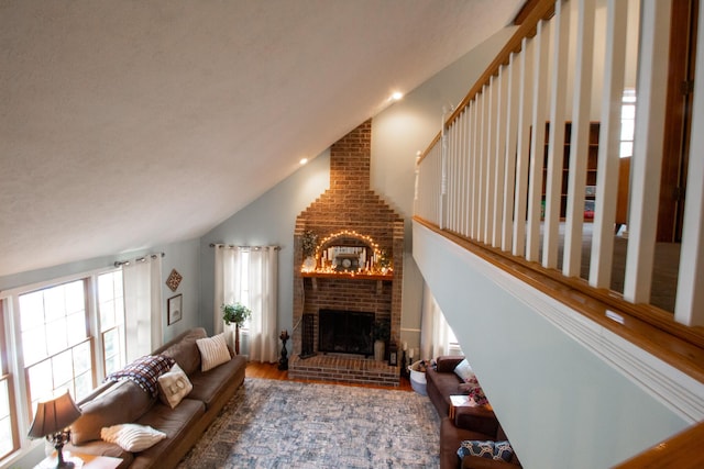 living room with a healthy amount of sunlight, wood-type flooring, high vaulted ceiling, and a brick fireplace