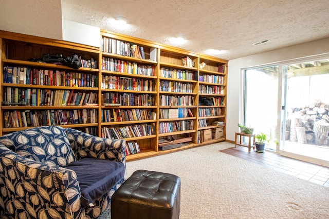 sitting room featuring a textured ceiling and carpet flooring