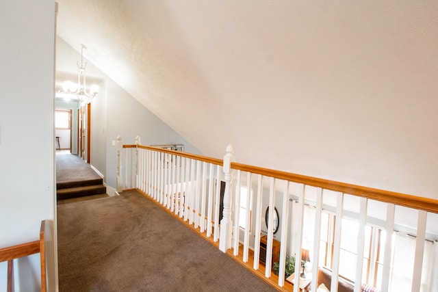 hallway with lofted ceiling, a chandelier, and carpet flooring