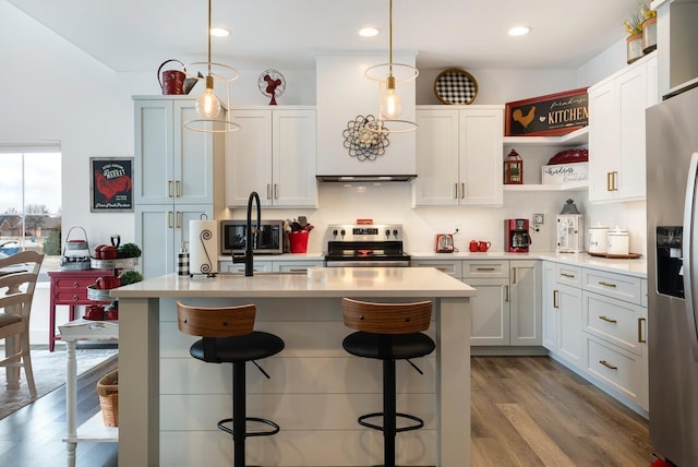 kitchen with a kitchen breakfast bar, pendant lighting, white cabinets, and stainless steel appliances