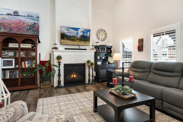 living room with dark wood-type flooring, high vaulted ceiling, and a brick fireplace