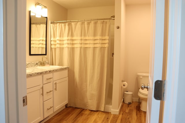 bathroom featuring toilet, vanity, a shower with shower curtain, and hardwood / wood-style flooring