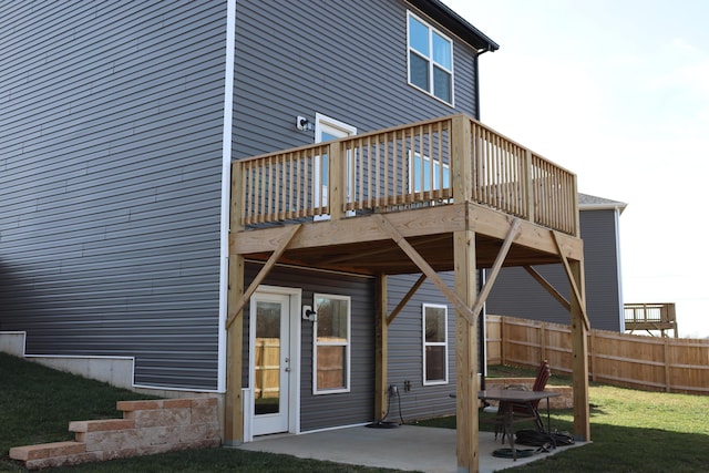 back of property with a wooden deck, a yard, and a patio