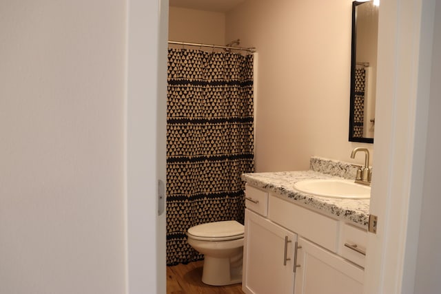 bathroom featuring toilet, walk in shower, hardwood / wood-style flooring, and vanity