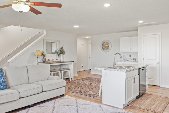 kitchen featuring light hardwood / wood-style floors, a kitchen island with sink, stainless steel dishwasher, white cabinets, and sink