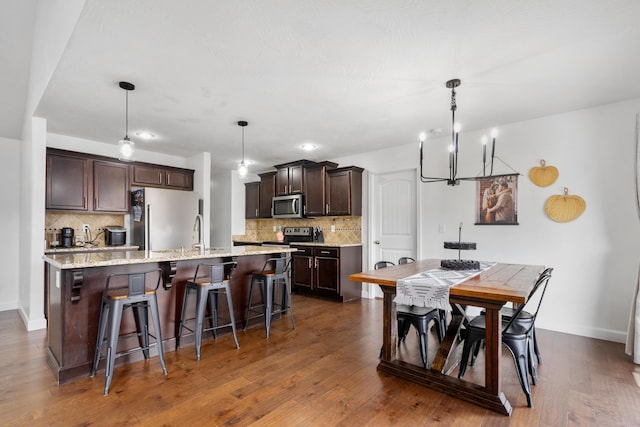 kitchen with appliances with stainless steel finishes, decorative light fixtures, an inviting chandelier, and a center island with sink