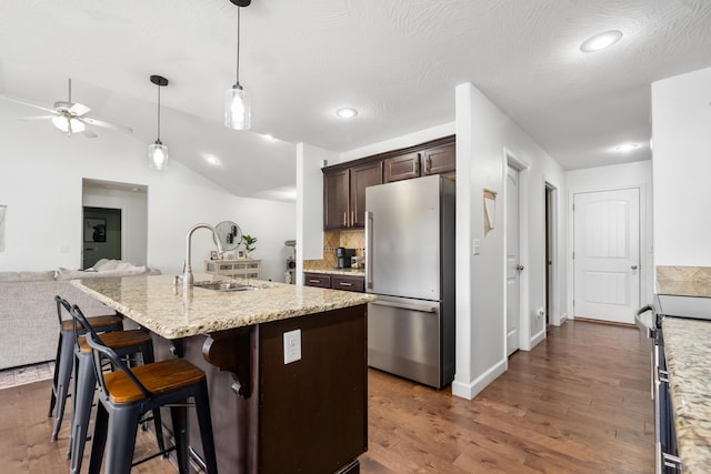 kitchen featuring sink, an island with sink, a breakfast bar area, dark brown cabinets, and appliances with stainless steel finishes