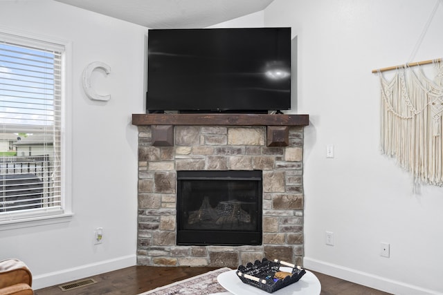 interior details with a fireplace, visible vents, wood finished floors, and baseboards