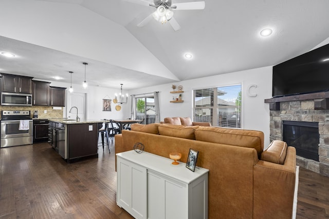 living area with recessed lighting, vaulted ceiling, ceiling fan with notable chandelier, a fireplace, and dark wood-type flooring