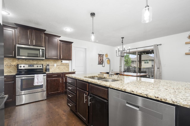 kitchen featuring light stone counters, a sink, stainless steel appliances, dark wood-style flooring, and backsplash