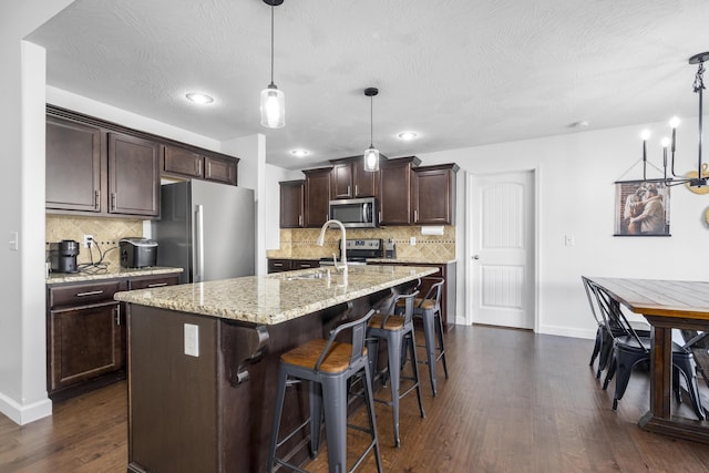 kitchen featuring dark brown cabinetry, a sink, stainless steel appliances, and decorative backsplash