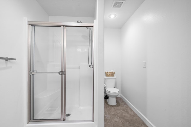 bathroom featuring toilet, visible vents, a shower stall, and baseboards