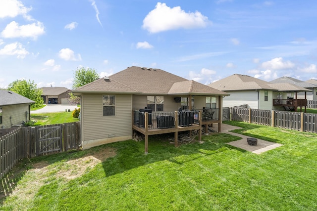 back of house featuring an outdoor fire pit, a wooden deck, a fenced backyard, and a lawn