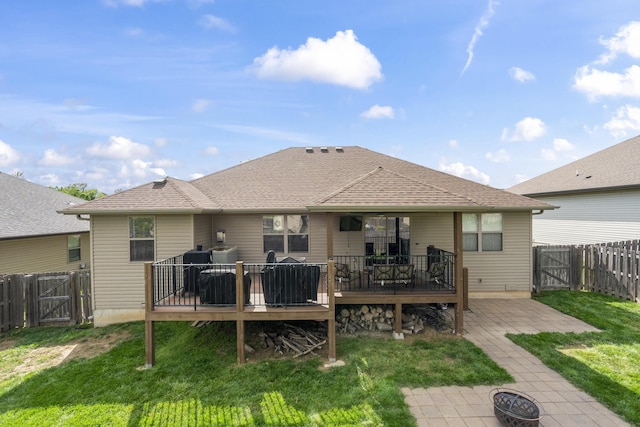 rear view of property featuring a gate, an outdoor fire pit, a deck, and a fenced backyard