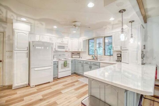 kitchen featuring kitchen peninsula, pendant lighting, white appliances, a breakfast bar area, and white cabinets