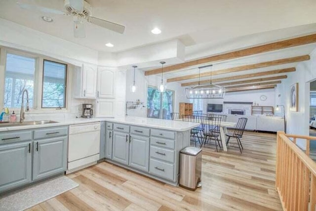 kitchen featuring kitchen peninsula, white dishwasher, sink, beam ceiling, and gray cabinets