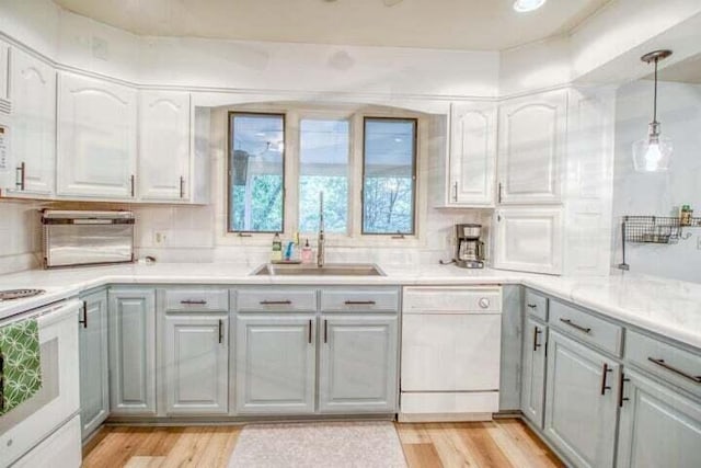 kitchen featuring light wood-type flooring, white appliances, gray cabinets, and sink