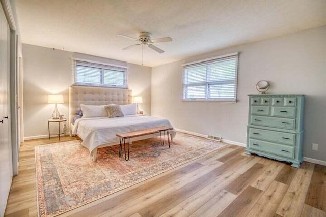 bedroom with ceiling fan, light hardwood / wood-style floors, and multiple windows