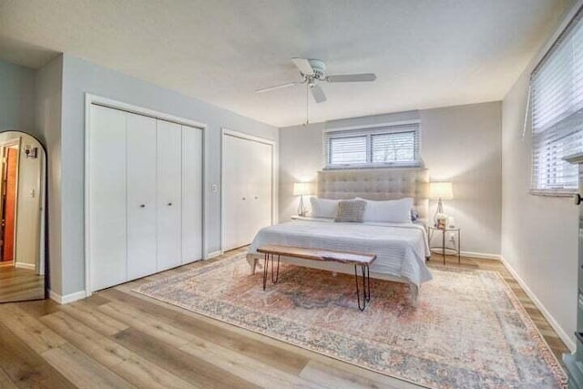 bedroom with multiple closets, ceiling fan, and light hardwood / wood-style flooring