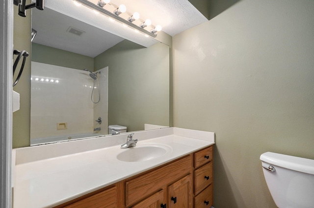 full bathroom with shower / tub combination, vanity, a textured ceiling, and toilet