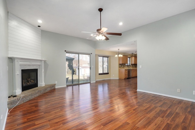 unfurnished living room with a fireplace, ceiling fan with notable chandelier, and dark hardwood / wood-style floors