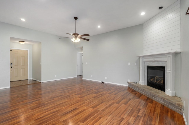 unfurnished living room with a premium fireplace, ceiling fan, and dark hardwood / wood-style floors