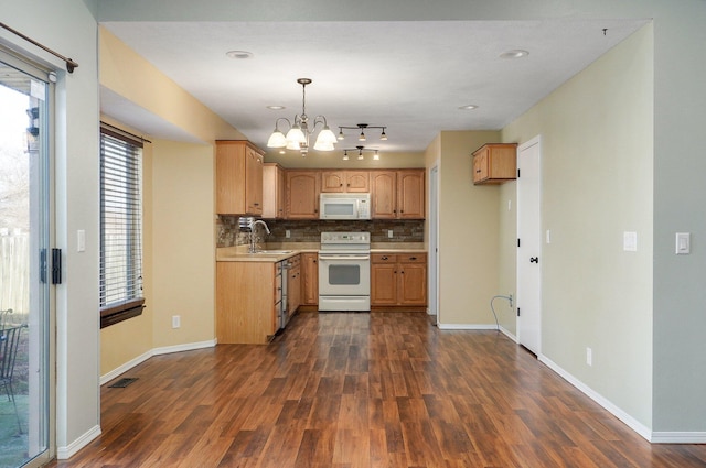 kitchen with white appliances, sink, decorative light fixtures, an inviting chandelier, and dark hardwood / wood-style floors