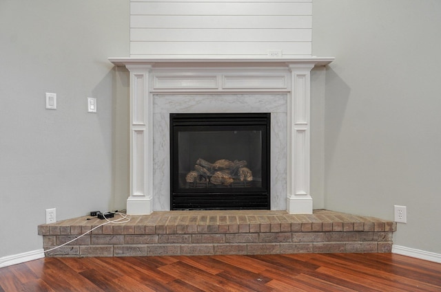 room details with a high end fireplace and hardwood / wood-style flooring