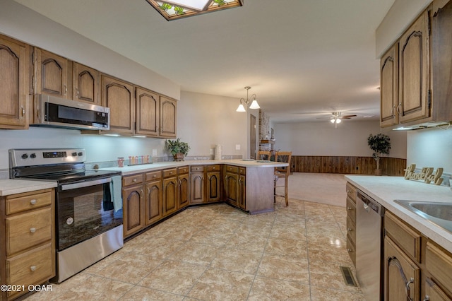 kitchen with a breakfast bar, ceiling fan with notable chandelier, light tile patterned floors, decorative light fixtures, and stainless steel appliances