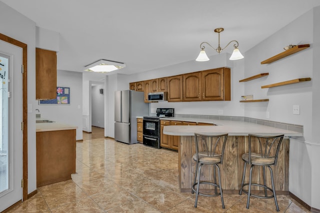 kitchen featuring kitchen peninsula, a kitchen bar, stainless steel appliances, a notable chandelier, and hanging light fixtures