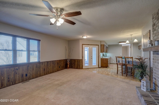 interior space featuring a fireplace, a textured ceiling, ceiling fan, and wooden walls