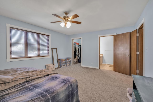 bedroom with light carpet, ceiling fan, a spacious closet, connected bathroom, and a closet