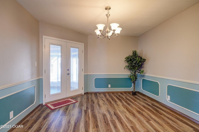 entryway with french doors, a chandelier, and wood-type flooring