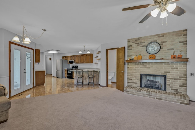 unfurnished living room with ceiling fan, light colored carpet, and a fireplace