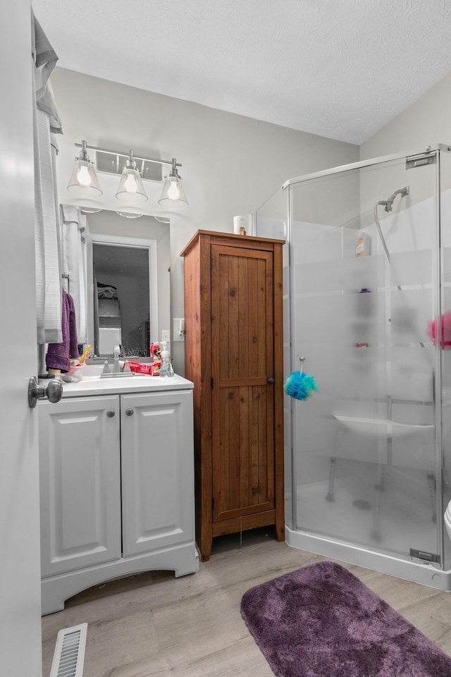 bathroom with hardwood / wood-style floors, vanity, and an enclosed shower