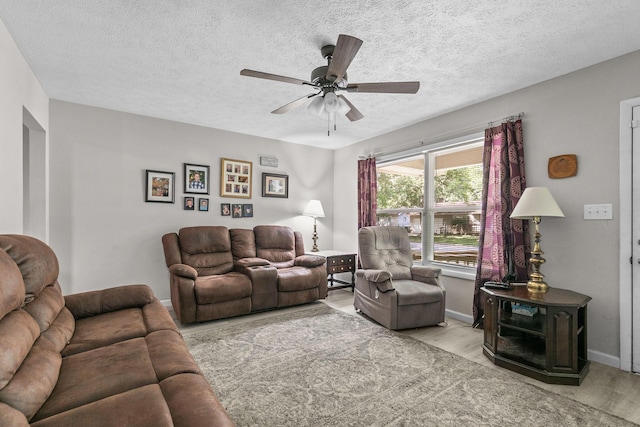 living room featuring ceiling fan and a textured ceiling