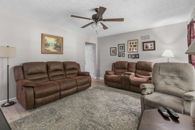 living room with ceiling fan, a textured ceiling, and hardwood / wood-style flooring