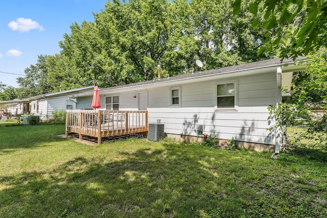 rear view of house with central AC unit, a wooden deck, and a lawn