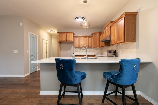 kitchen featuring sink, decorative backsplash, stainless steel electric range oven, dark hardwood / wood-style flooring, and kitchen peninsula