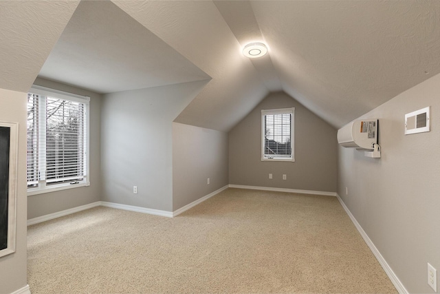 additional living space featuring an AC wall unit, light carpet, and lofted ceiling