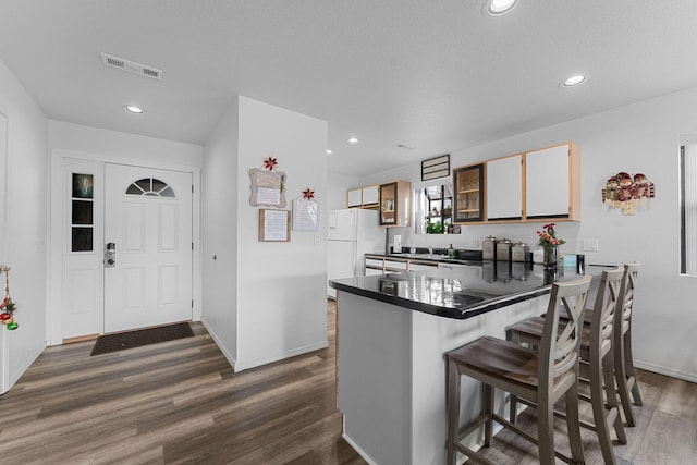 kitchen with dark hardwood / wood-style floors, white refrigerator, a kitchen breakfast bar, and kitchen peninsula