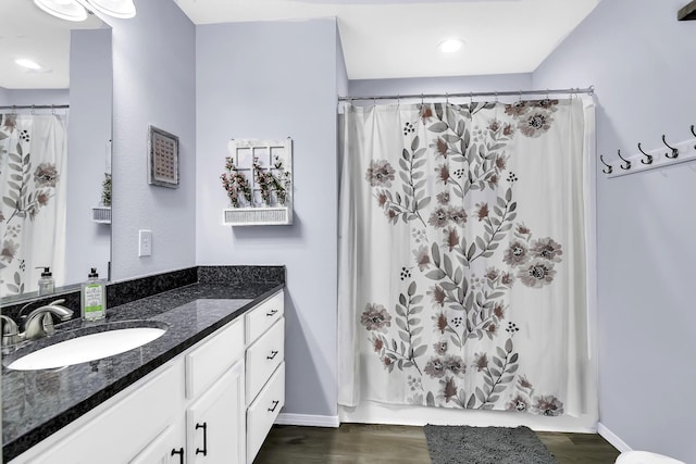 bathroom with wood-type flooring, vanity, and shower / bath combo with shower curtain