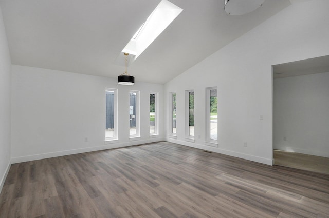 spare room featuring a skylight, high vaulted ceiling, and dark wood-type flooring