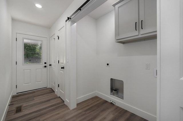 clothes washing area featuring electric dryer hookup, a barn door, cabinets, and dark hardwood / wood-style floors