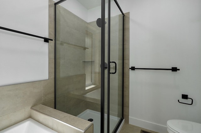 bathroom with a shower with shower door and toilet