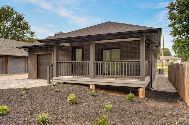 view of front of house with a porch, a garage, and central air condition unit