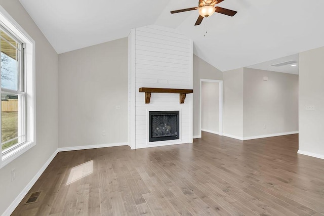 unfurnished living room with ceiling fan, wood-type flooring, a fireplace, and vaulted ceiling