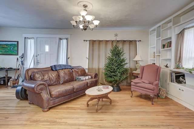 living room featuring built in features, light hardwood / wood-style floors, and an inviting chandelier