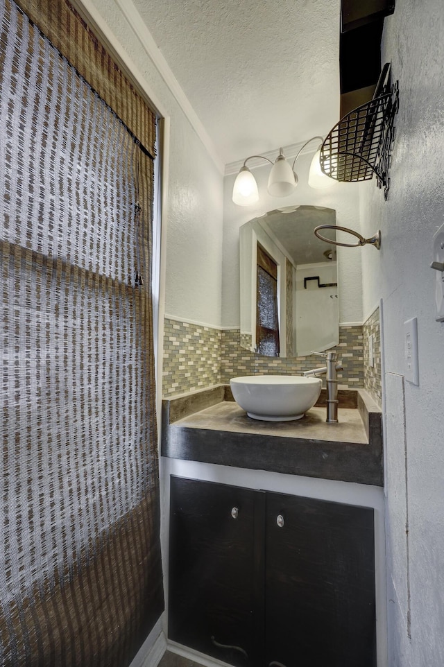 bathroom with vanity, crown molding, a textured ceiling, and tasteful backsplash