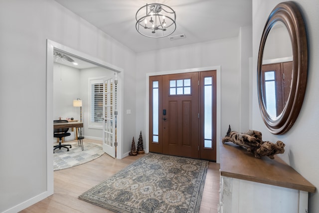 entryway with ceiling fan with notable chandelier and light hardwood / wood-style flooring